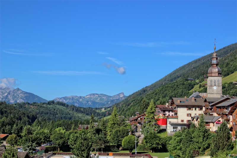 Pretty Alpine village with a stunning backdrop of mountains under a blue sky